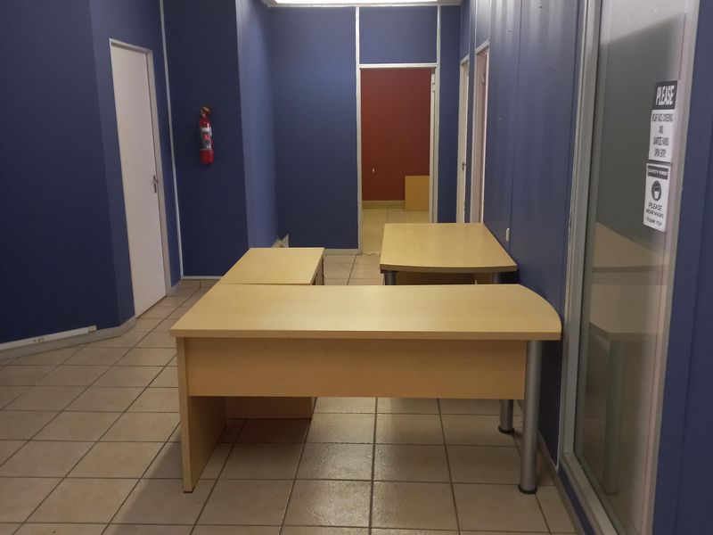 A functional office space featuring ceramic tiled flooring, blue painted walls, and a glass partition, providing a clean and professional work environment.