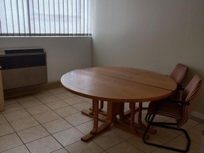 A functional office space featuring ceramic tile flooring, vertical window blinds, and a built-in HVAC unit.