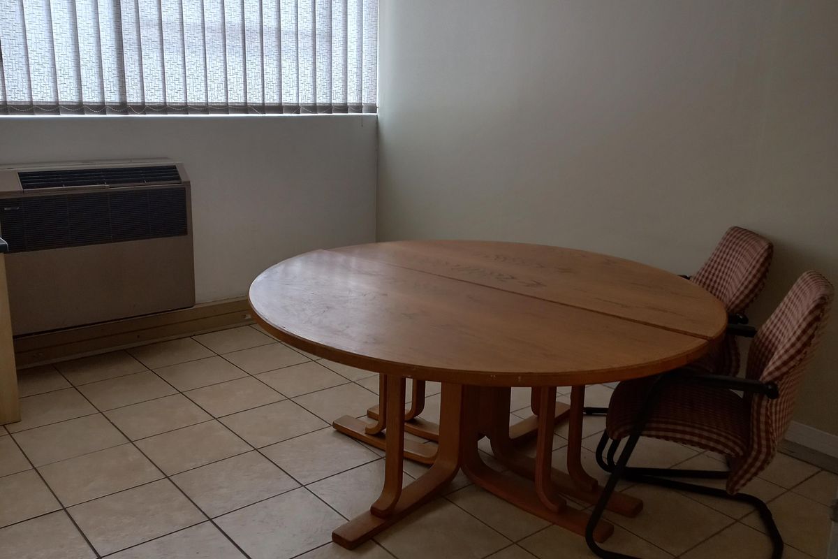 A functional office space featuring ceramic tile flooring, vertical window blinds, and a built-in HVAC unit.