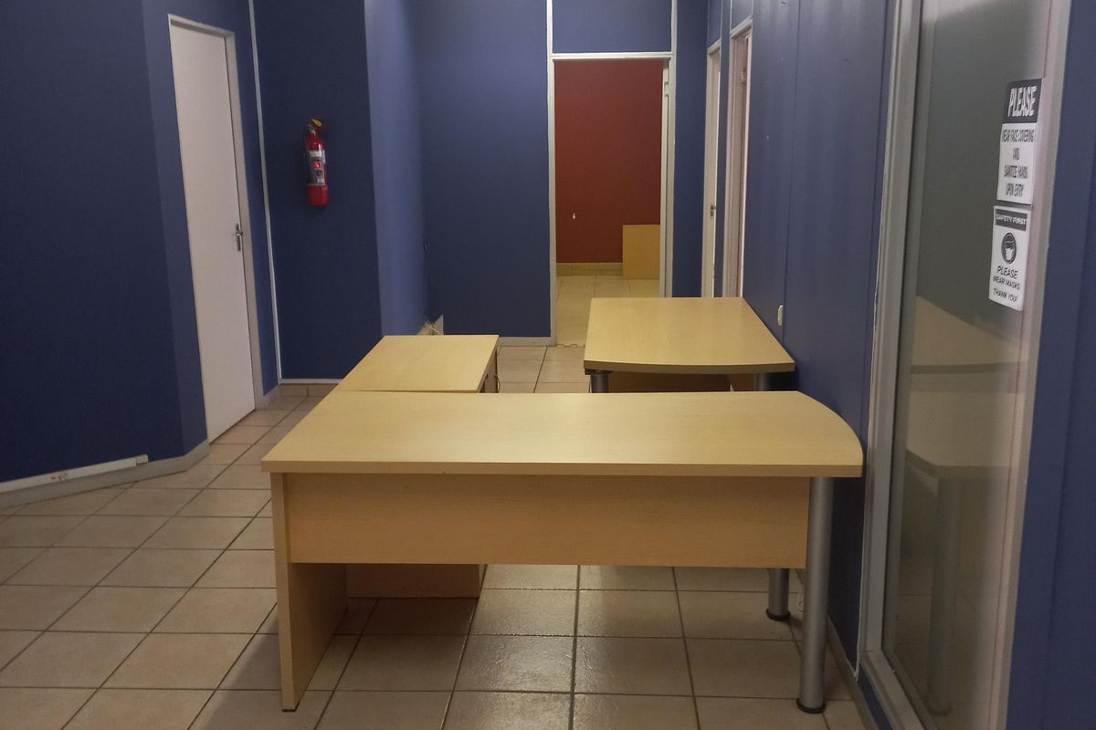 A functional office space featuring ceramic tiled flooring, blue painted walls, and a glass partition, providing a clean and professional work environment.
