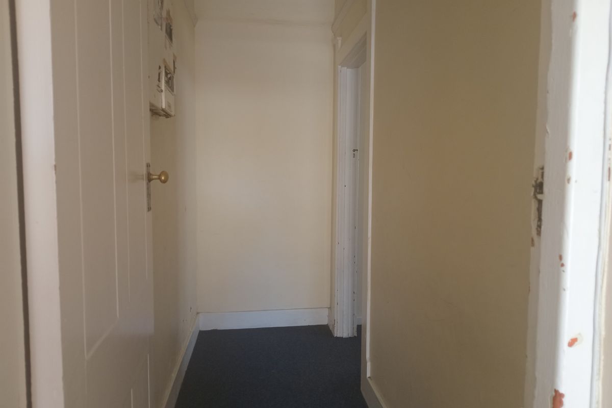 A narrow interior hallway featuring painted walls, carpeted flooring, and standard internal door frames.
