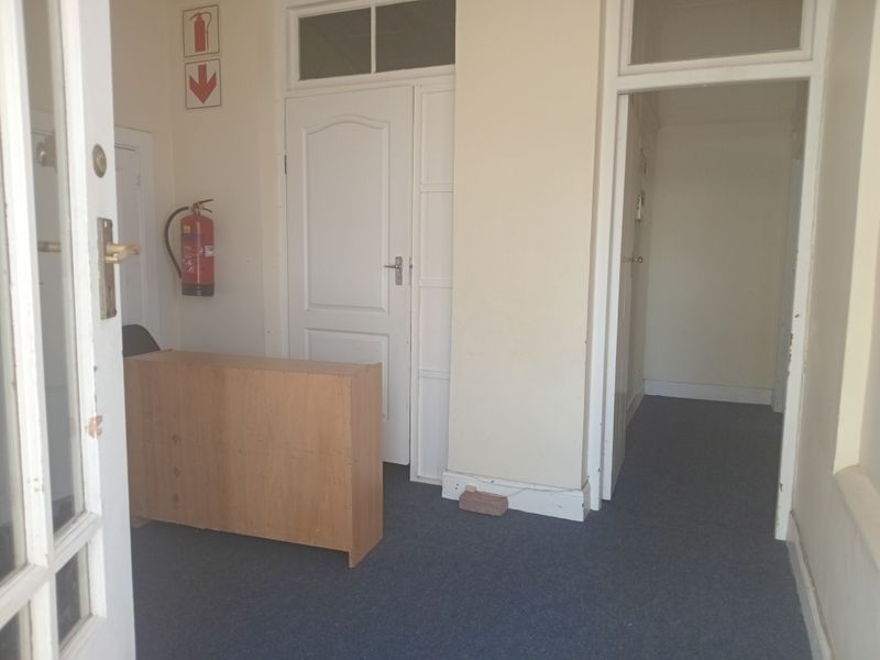 A functional office entry area featuring carpeted flooring, internal doors, and wall-mounted fire safety equipment.