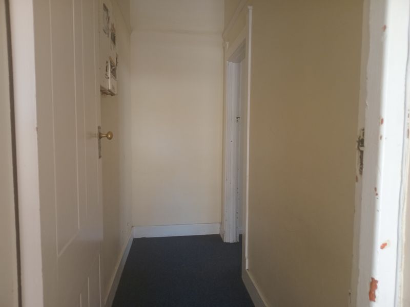 A narrow interior hallway featuring painted walls, carpeted flooring, and standard internal door frames.