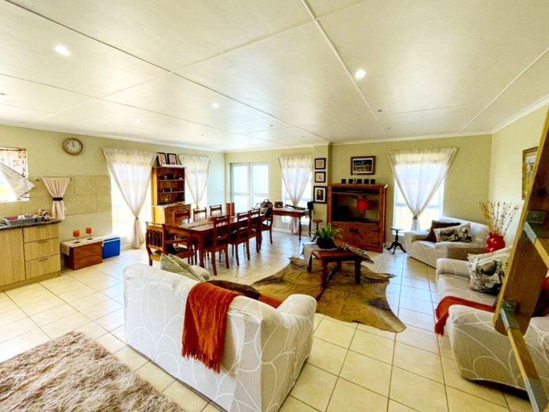 Spacious open-plan living and dining area featuring tiled flooring, recessed lighting, and an integrated kitchen corner with cabinetry and sink.