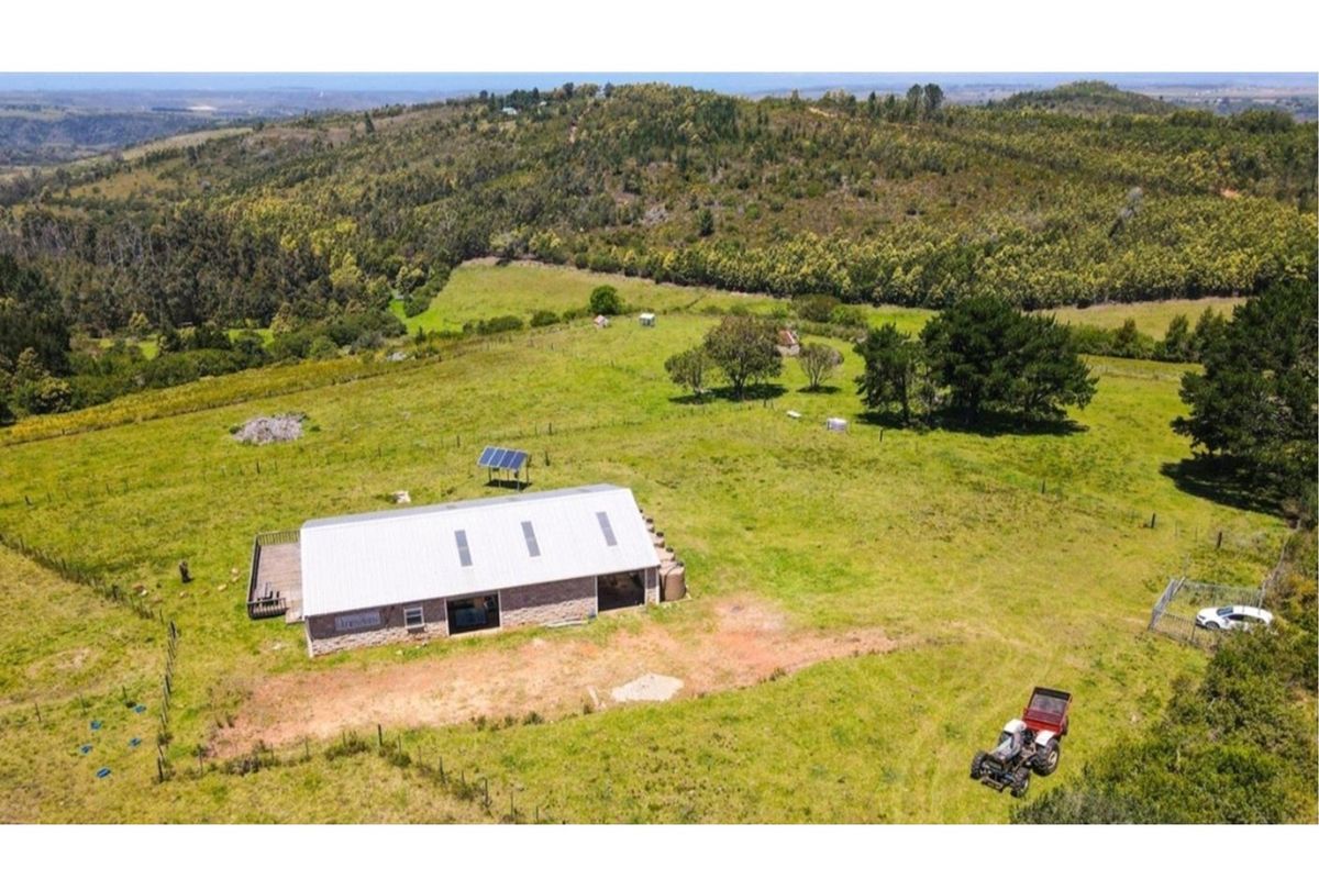 Aerial view of a rural farm property featuring a building with a metal roof, solar panels, and surrounding pasture land.