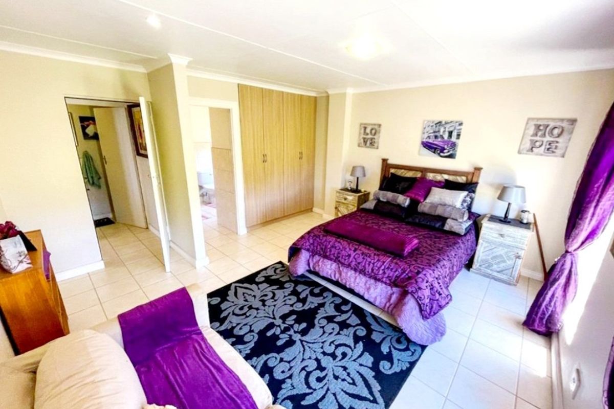 A bedroom featuring built-in cupboards, tiled flooring, and recessed ceiling lighting, with an adjoining en-suite bathroom visible.