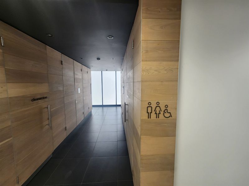 Modern office hallway featuring high-quality timber veneer wall paneling, integrated doors, and dark tiled flooring with recessed lighting.