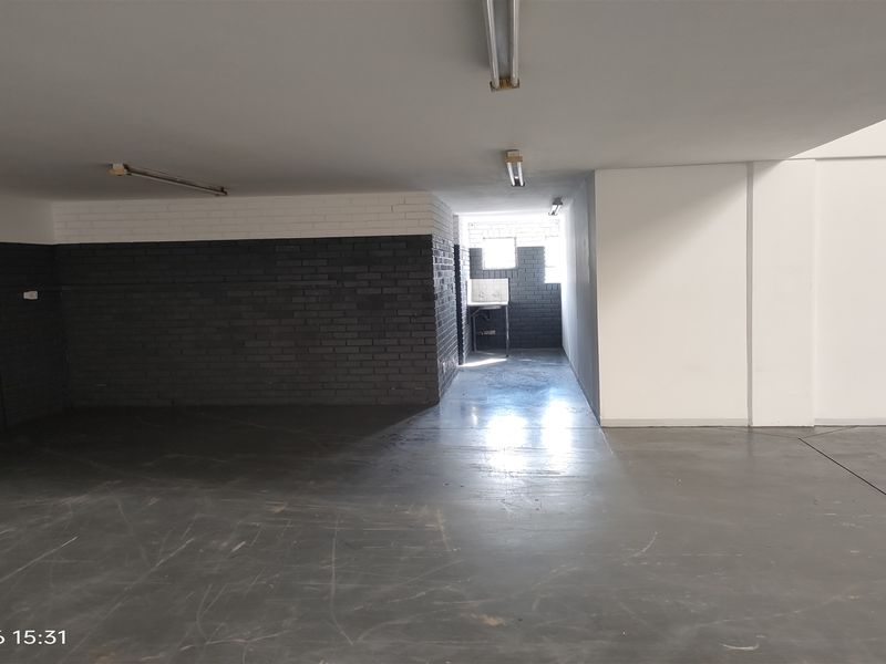 An open-plan industrial utility space featuring painted brick walls, concrete flooring, and a dedicated utility sink area with natural light.