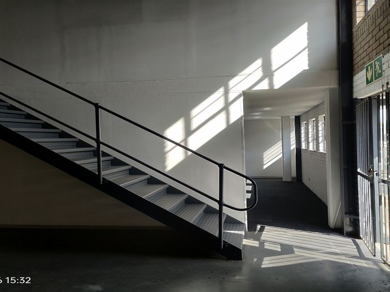 Industrial interior space featuring a metal staircase, exposed brickwork, and secure access points, offering a clean, functional layout suitable for various commercial uses.