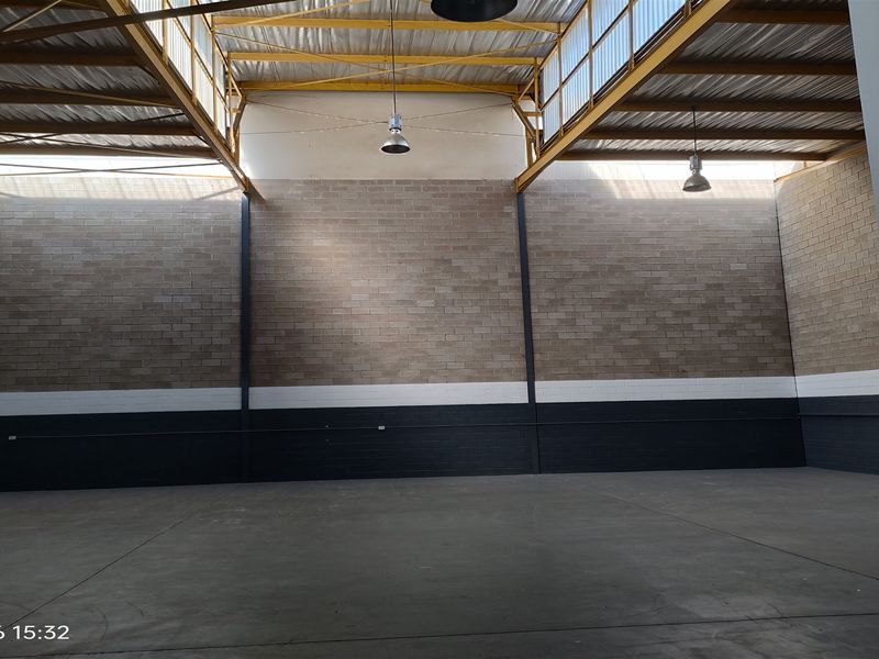 Spacious industrial utility area featuring high ceilings with exposed steel trusses, natural light from skylights, and durable concrete flooring.