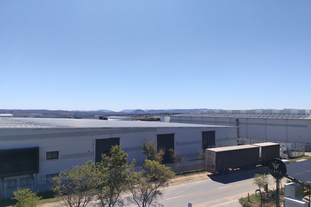 Aerial view of an industrial park featuring large warehouse facilities with metal cladding, roller shutter doors, and paved access roads.