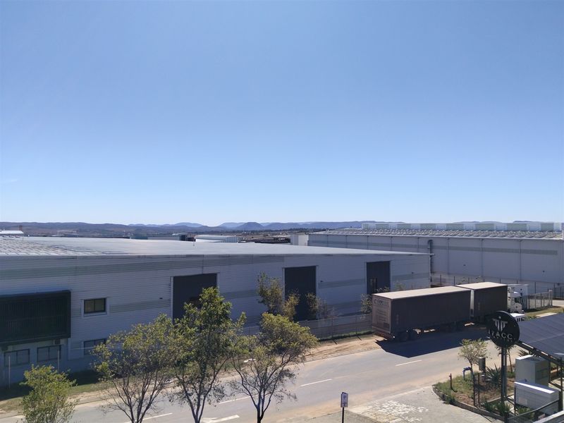 Aerial view of an industrial park featuring large warehouse facilities with metal cladding, roller shutter doors, and paved access roads.