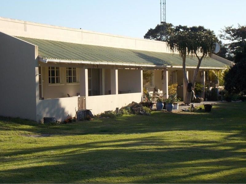 A view of the rear exterior of the farm property, featuring a long covered patio area and a spacious lawn.