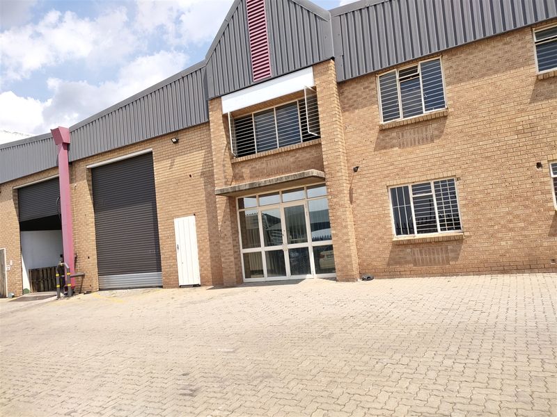 Front elevation of an industrial property featuring face brick construction, roller shutter access, and paved exterior yard space.