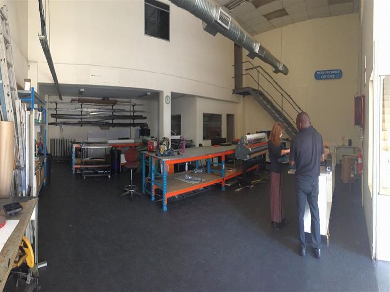 Spacious industrial utility area featuring high ceilings, exposed ductwork, a metal staircase leading to a mezzanine, and durable industrial flooring.