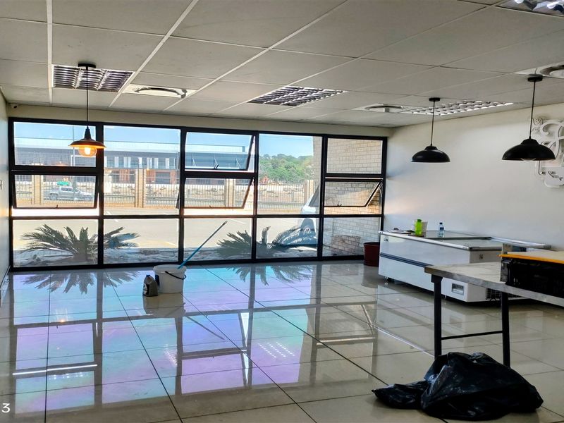Open plan industrial space featuring large glass windows, polished tiled flooring, suspended ceiling, and modern pendant lighting, suitable for retail or office use.