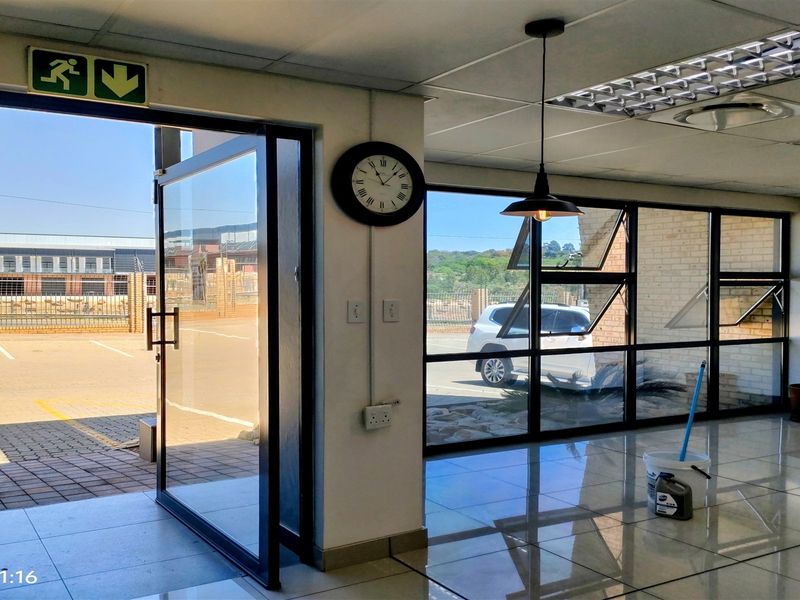 Bright industrial entrance area featuring tiled flooring, suspended ceiling, and large aluminium-framed windows providing ample natural light and exterior views.