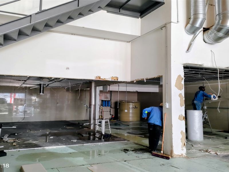 Industrial utility space undergoing renovation, featuring exposed ductwork, a steel staircase, and tiled wall sections with ongoing construction work visible.