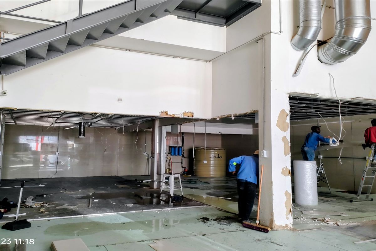Industrial utility space undergoing renovation, featuring exposed ductwork, a steel staircase, and tiled wall sections with ongoing construction work visible.