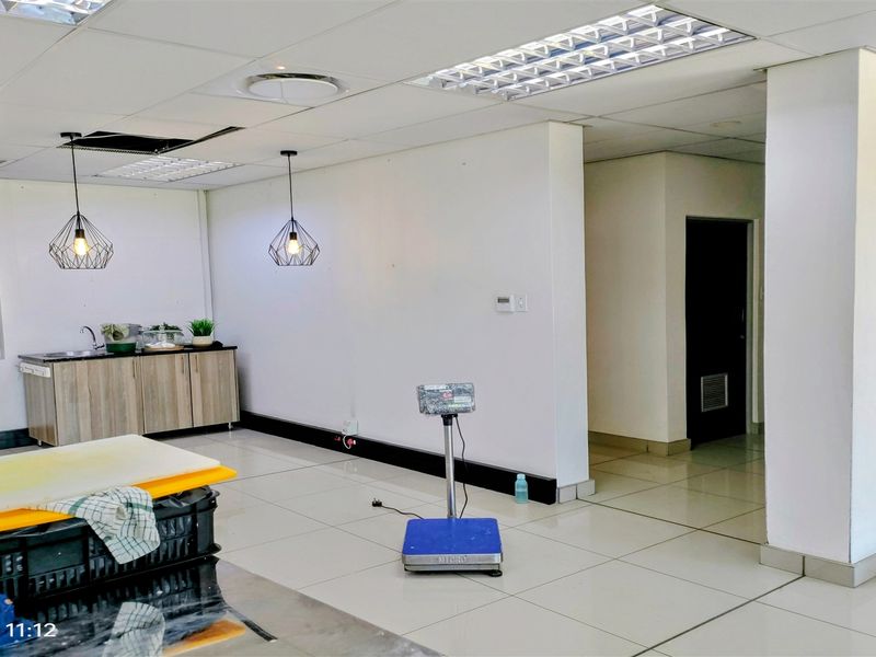 A functional utility or prep area featuring tiled flooring, built-in cabinetry with a sink, and suspended ceiling panels.