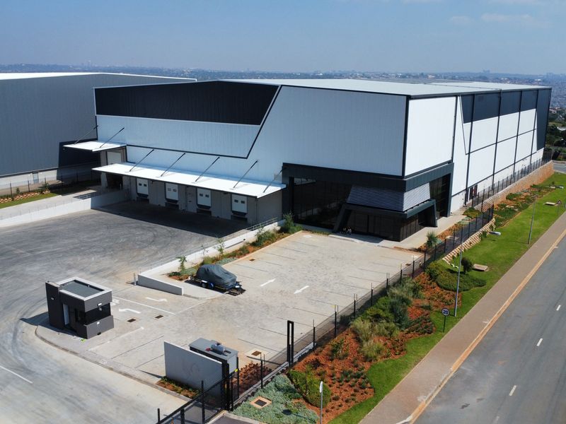 Aerial view of a modern industrial warehouse facility featuring multiple loading docks, a security guard house, and a paved yard area.