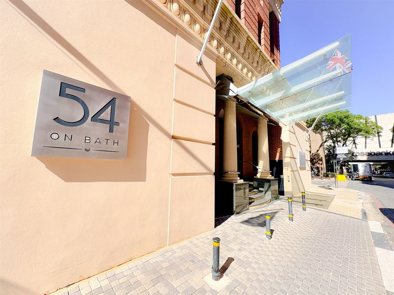 The front entrance of the office building features a modern glass canopy, stone columns, and professional signage on a well-maintained facade.