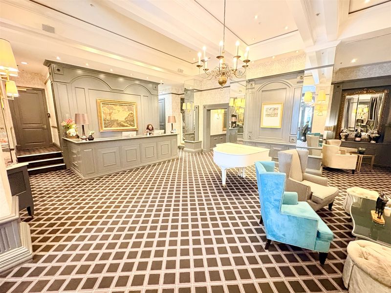 Elegant office reception area featuring a custom built-in reception desk, decorative wainscoting, sophisticated lighting fixtures, and high-end finishes throughout the lobby space.