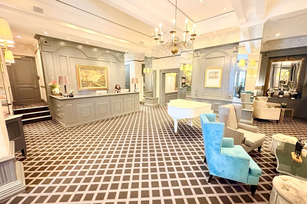 Elegant office reception area featuring a custom built-in reception desk, decorative wainscoting, sophisticated lighting fixtures, and high-end finishes throughout the lobby space.