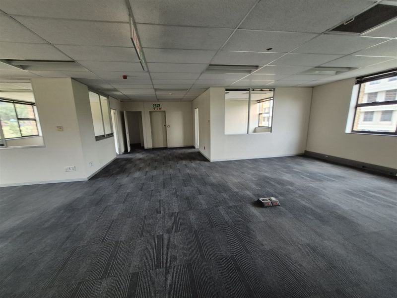 Spacious open-plan office area featuring carpet tiles, suspended ceilings, and internal glass partitions, providing a versatile workspace environment.