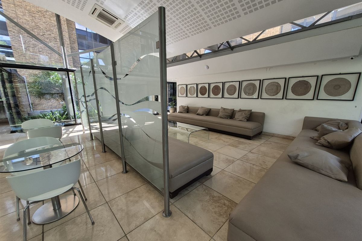 Modern office reception or lounge area featuring tiled flooring, glass partitions, and floor-to-ceiling windows providing ample natural light.