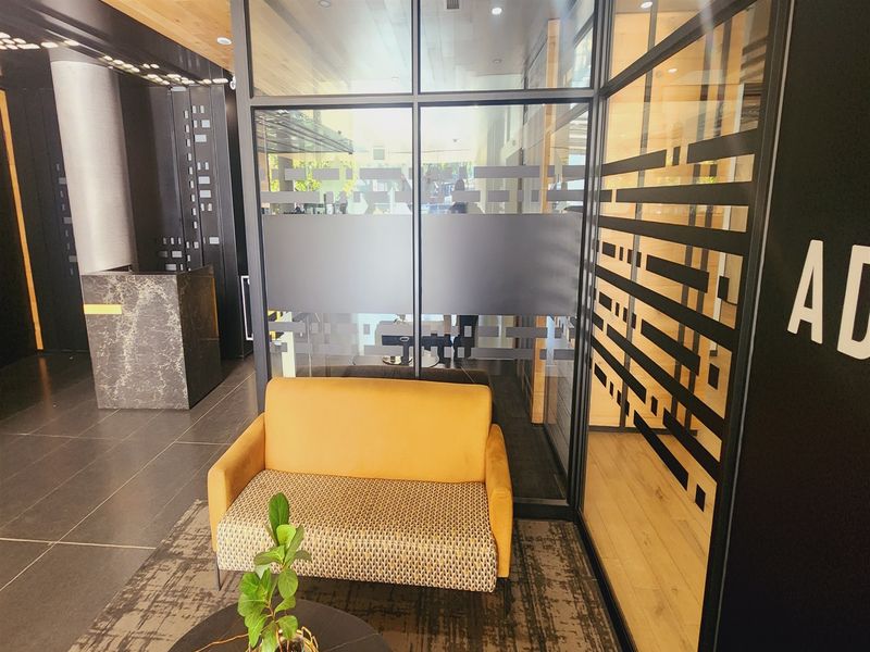 Modern office reception area featuring a sleek marble-look desk, glass partition walls with privacy film, and contemporary tiled flooring.