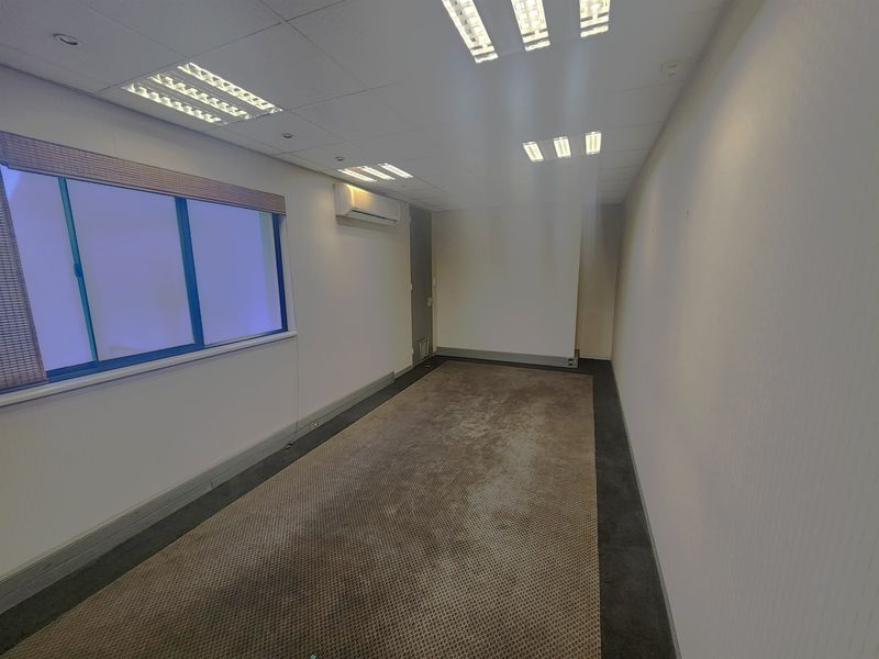 An empty office space featuring a suspended ceiling with recessed lighting, split-system air conditioning, and carpeted flooring.