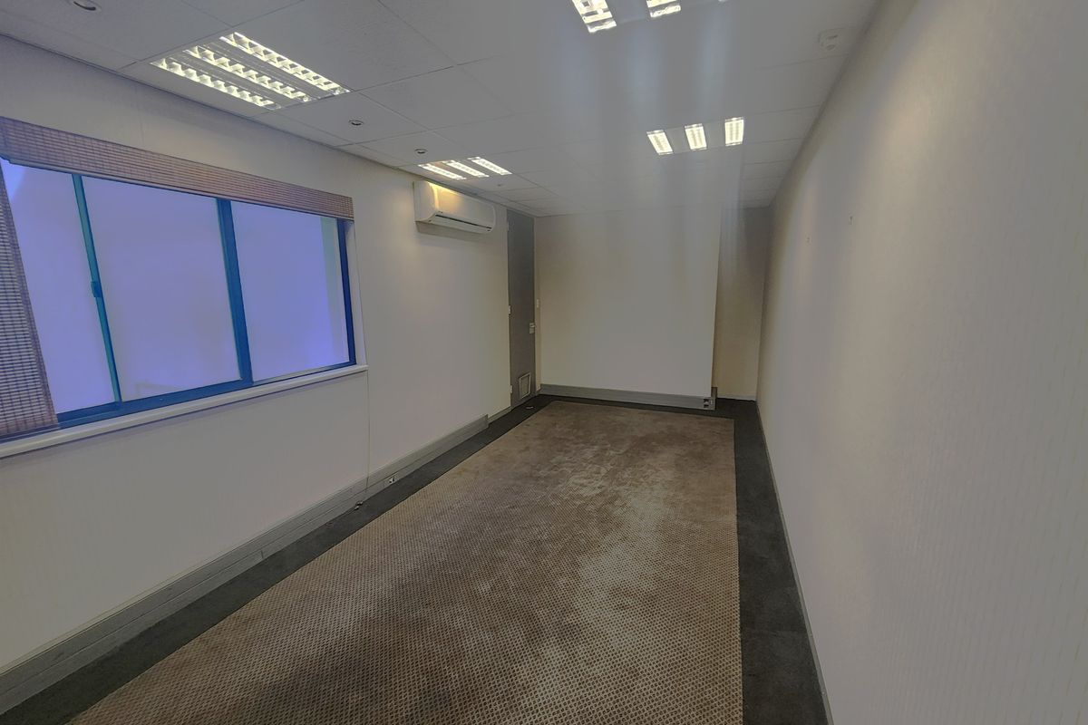 An empty office space featuring a suspended ceiling with recessed lighting, split-system air conditioning, and carpeted flooring.
