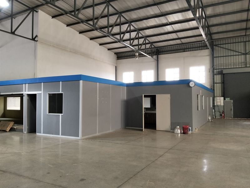 Spacious industrial warehouse featuring a high-clearance steel truss roof, polished concrete flooring, and a self-contained modular office structure.