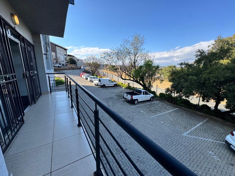 A clean, tiled balcony with a metal balustrade overlooking the office complex parking area.