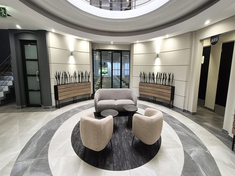 Modern office building entrance lobby featuring a circular architectural ceiling design, polished tiled flooring, and integrated recessed lighting.