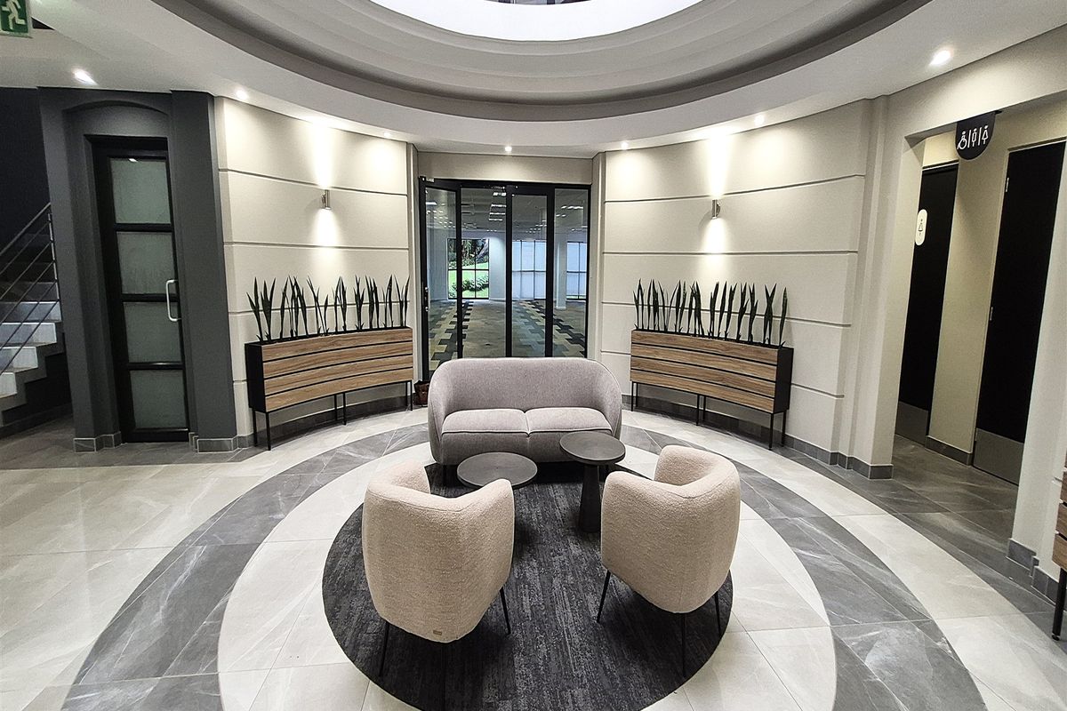Modern office building entrance lobby featuring a circular architectural ceiling design, polished tiled flooring, and integrated recessed lighting.