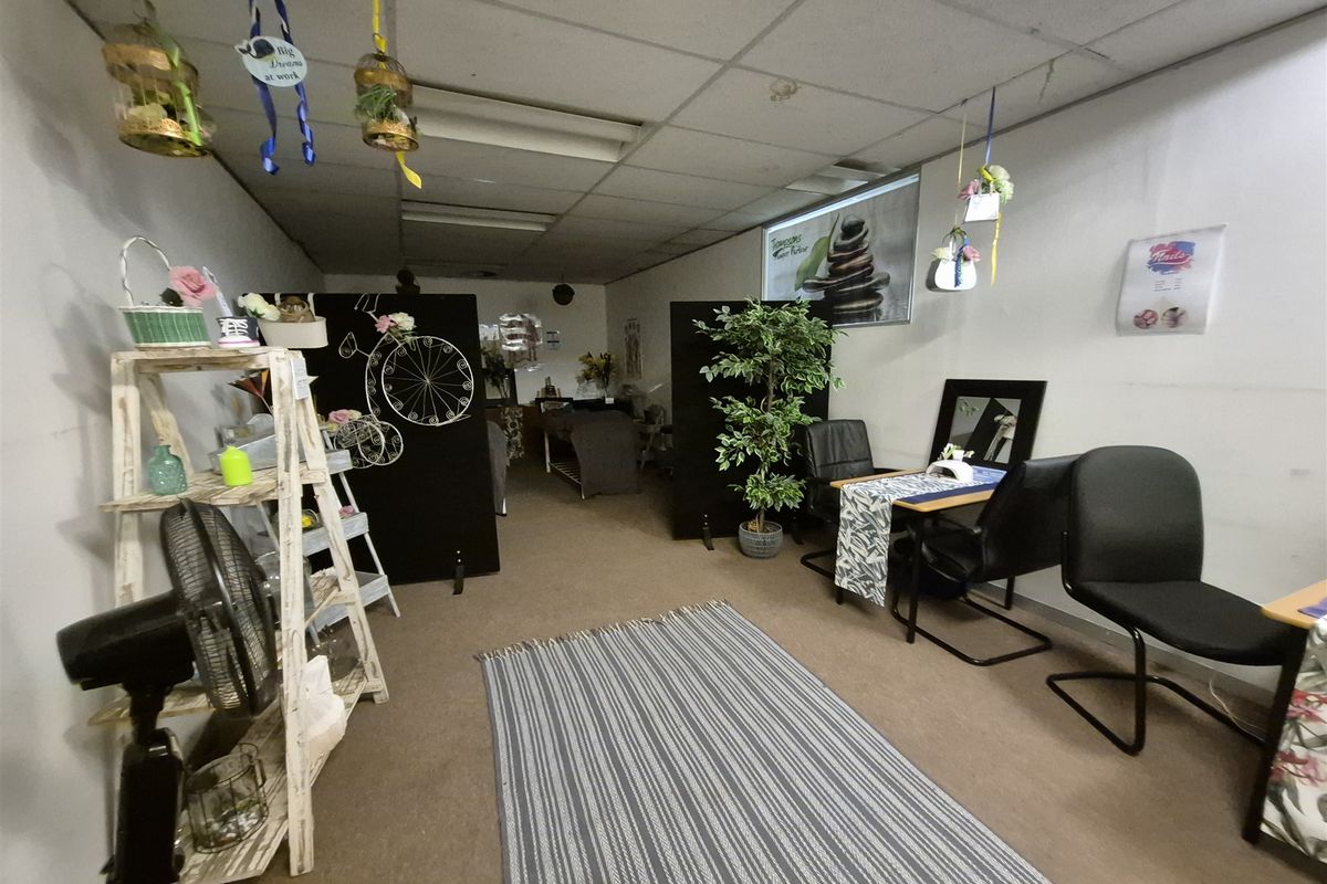 An office space currently utilized as a beauty salon, featuring a suspended ceiling and carpeted flooring, suitable for various commercial or professional office uses.