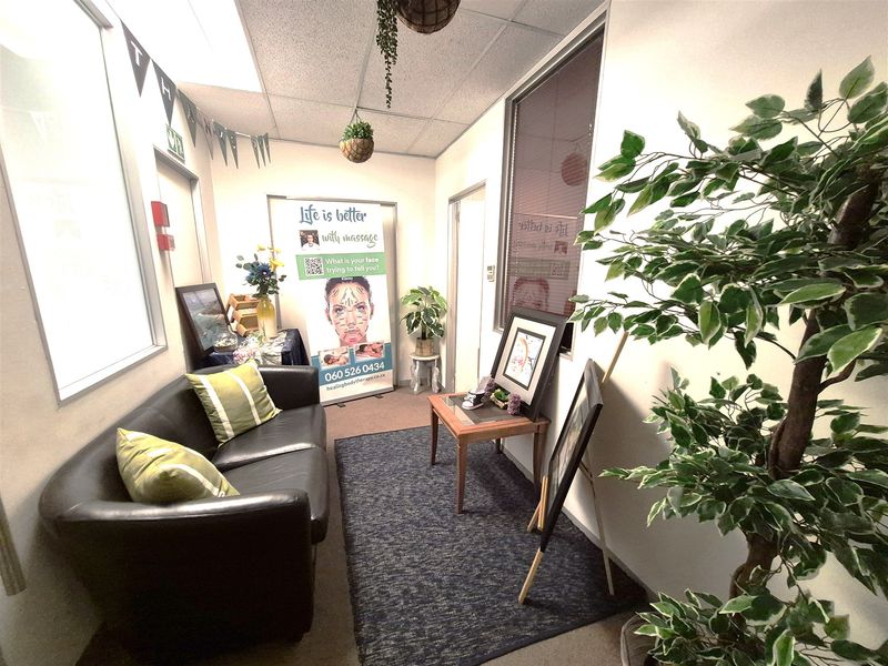 A compact office space featuring a suspended ceiling, carpeted flooring, and an internal glass partition, suitable for a professional workspace or consultation room.