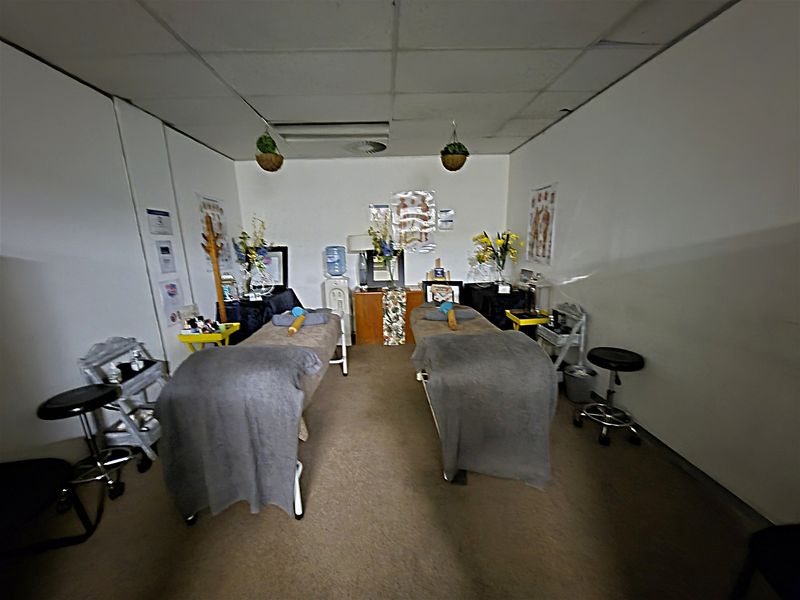A functional office or treatment room featuring a suspended ceiling with integrated air conditioning and carpeted flooring.