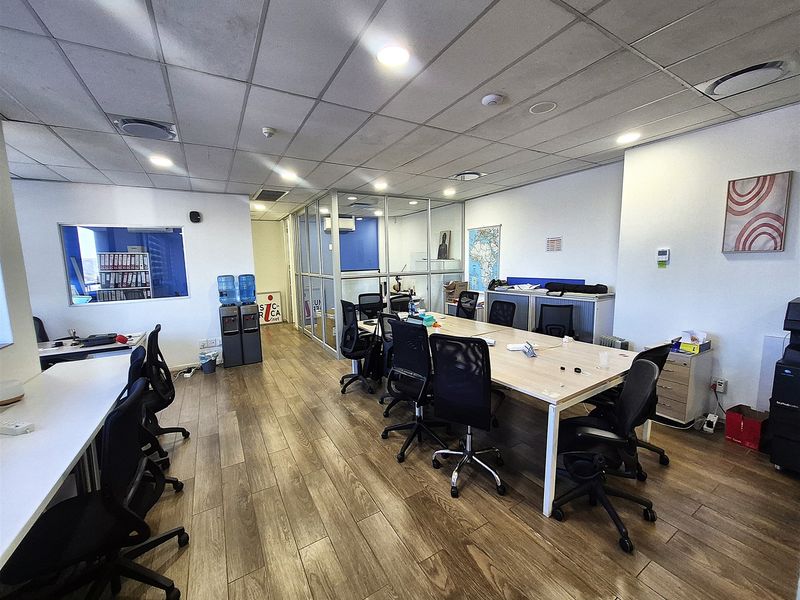 A professional office space featuring a suspended ceiling with recessed lighting, glass partitioning, and durable laminate flooring.