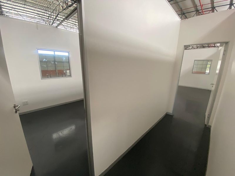 A clean, modern industrial hallway featuring smooth epoxy flooring, partition walls, and an exposed ceiling structure, providing a bright and functional workspace layout.