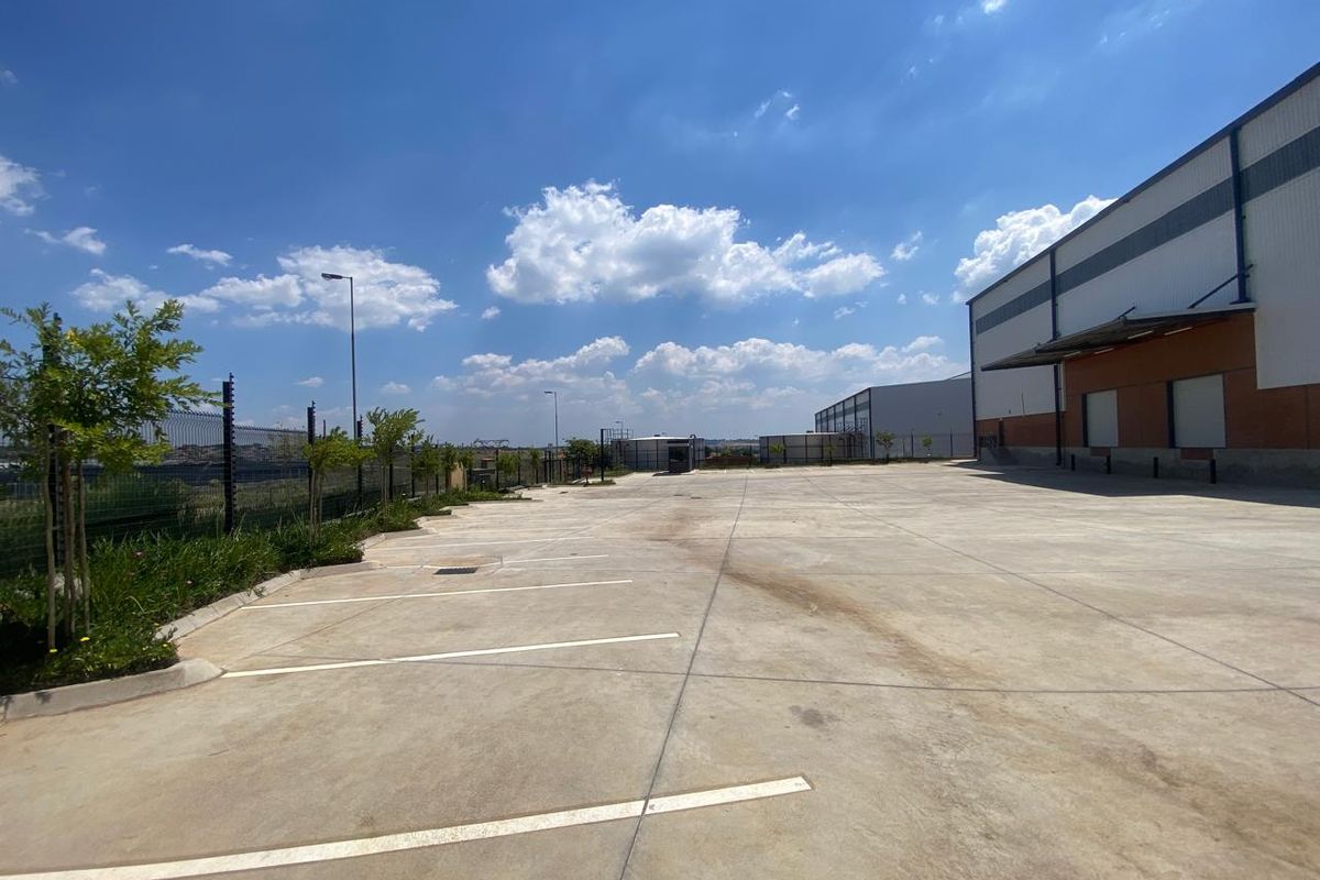 Spacious concrete industrial yard area featuring perimeter fencing and access to the warehouse loading bays under a structural canopy.