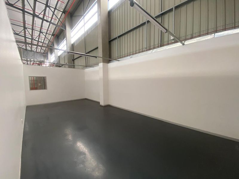 A clean, modern industrial utility space featuring polished epoxy flooring, high ceilings with exposed steel structure, and an internal viewing window.