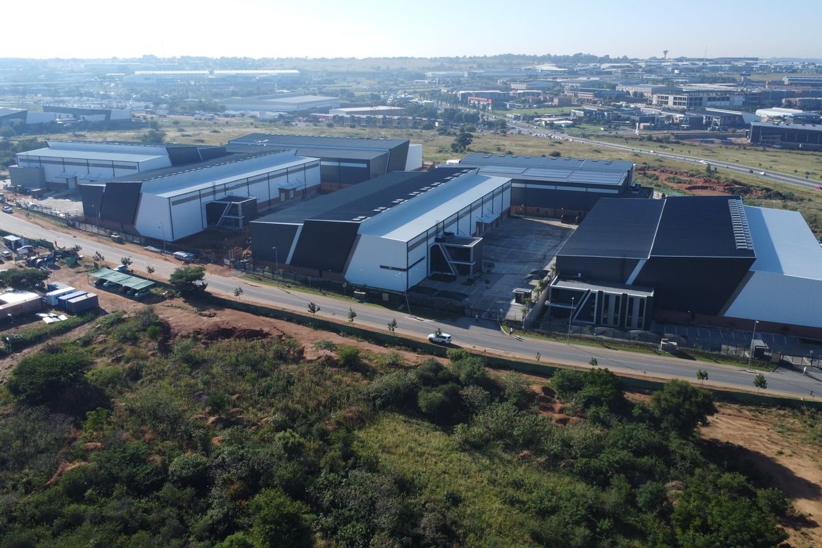 Aerial view of a modern industrial warehouse complex featuring large-scale storage facilities, solar panel installations, and paved loading yards within an established industrial park.