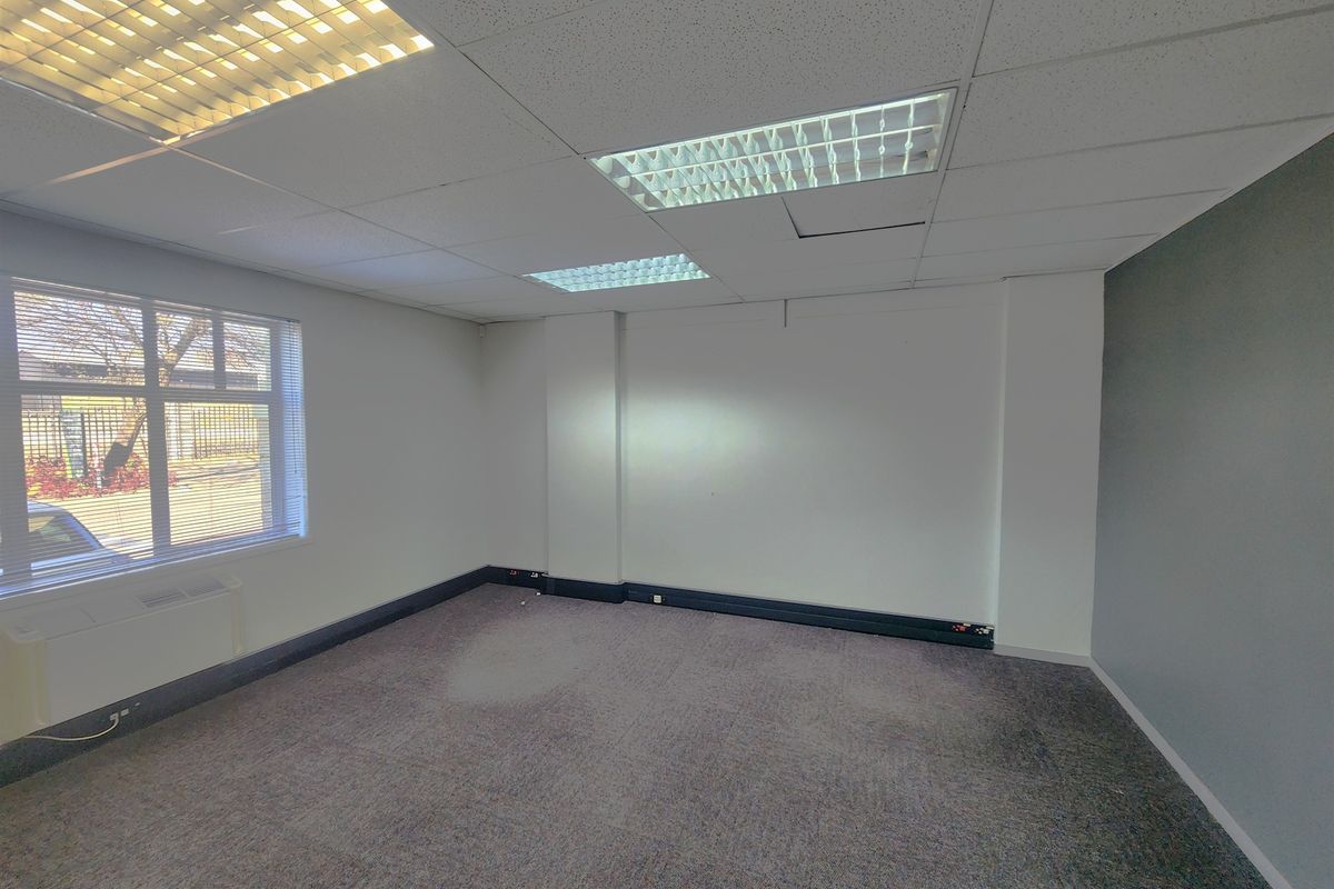 An empty office space featuring a suspended ceiling with recessed lighting, carpeted flooring, and perimeter trunking for electrical and data connectivity.