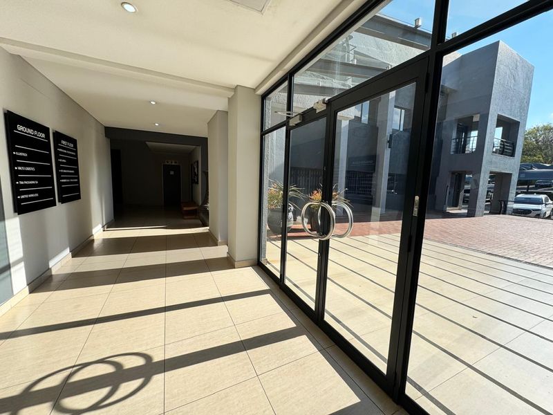 Modern office building entrance lobby featuring large glass doors, tiled flooring, and clear directory signage for ground and first floor tenants.