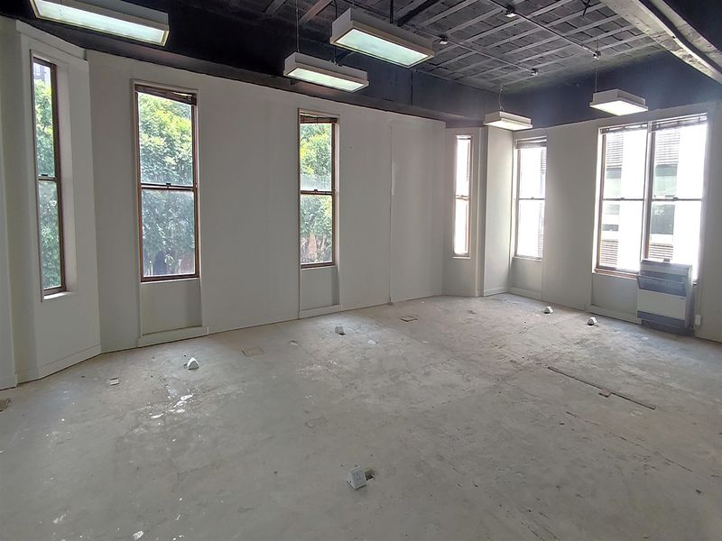An empty, open-plan office space featuring exposed ceilings, large windows, and unfinished concrete flooring, ready for custom fit-out.