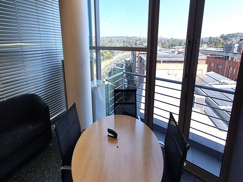 Modern office space featuring floor-to-ceiling windows with balcony access, providing ample natural light and expansive urban views.