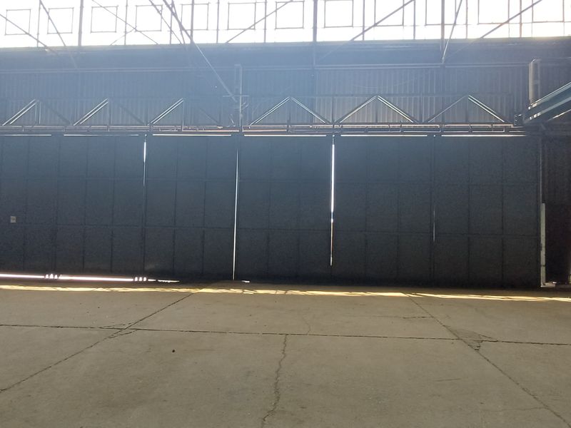 Spacious industrial warehouse interior featuring high ceilings, large sliding hangar-style doors, and durable concrete flooring suitable for heavy-duty operations.